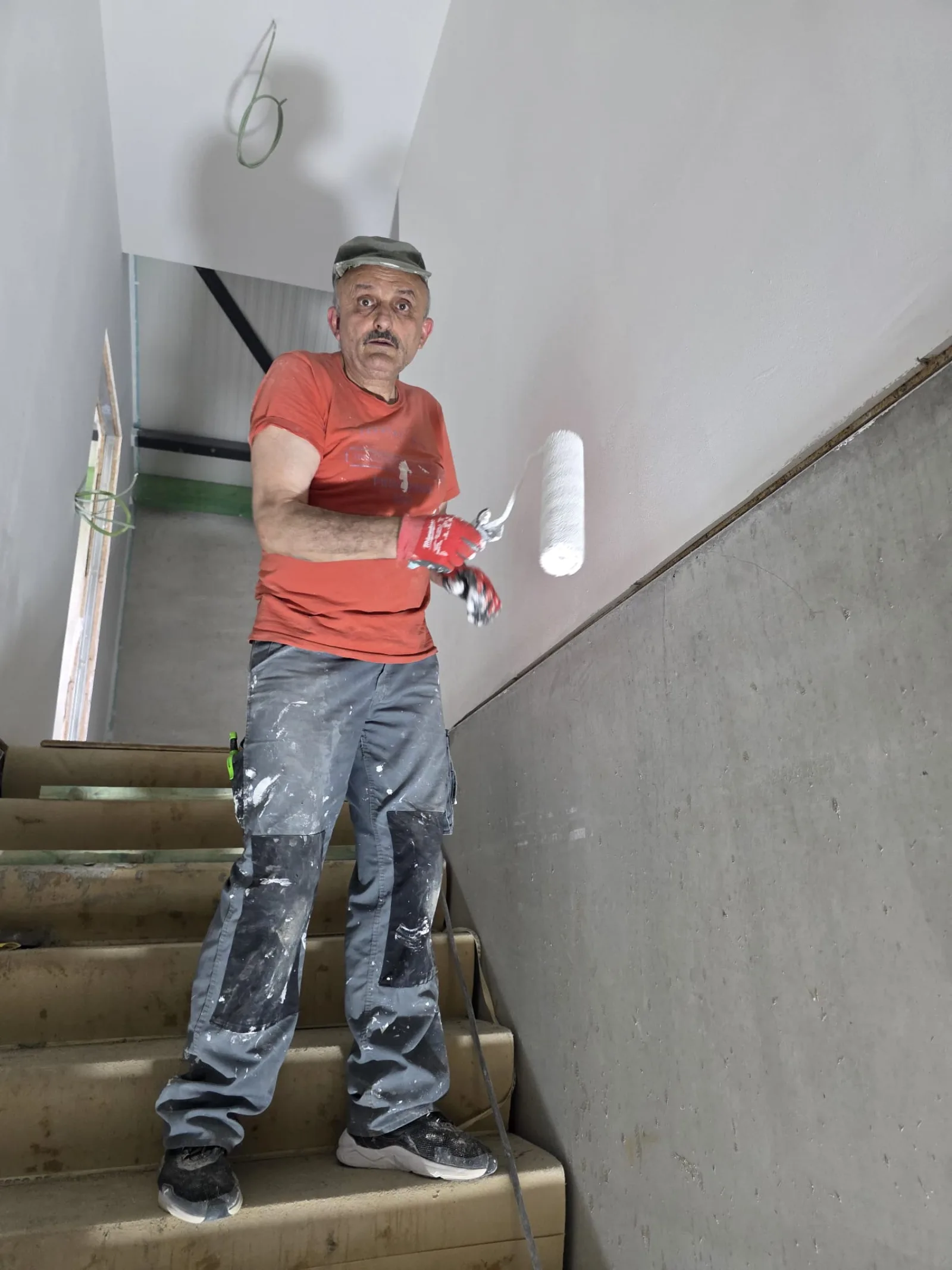 Peintre appliquant la sous-couche dans la cage d'escalier